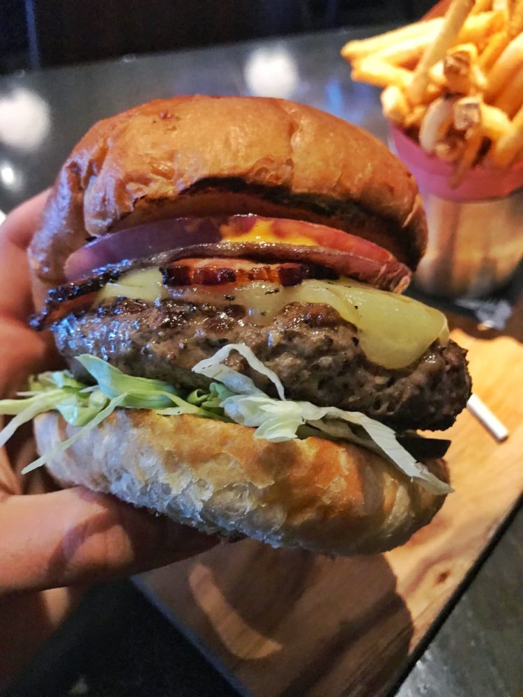 The Carbon Bar Cheeseburger: 8 oz beef patty, lettuce, charred red onion, pit smoked bacon, Thunder Oak gouda, dill pickle, ballpark mustard, smoked chili mayo from The Carbon Bar in Toronto. 