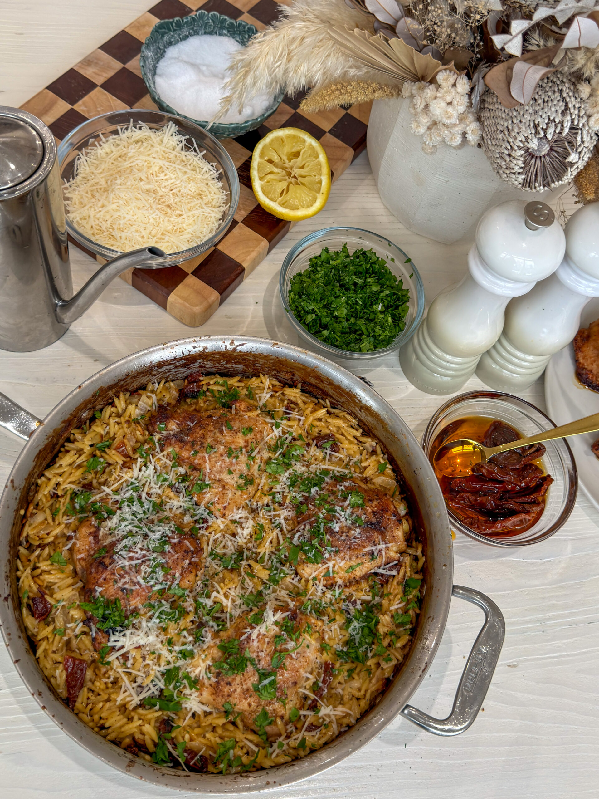 Golden seared chicken thighs nestled in creamy lemon sauce with sun-dried tomato orzo, garnished with fresh herbs